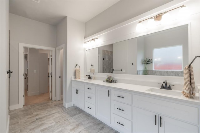 bathroom with double vanity, a sink, and a shower
