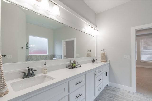 bathroom with double vanity, baseboards, and a sink