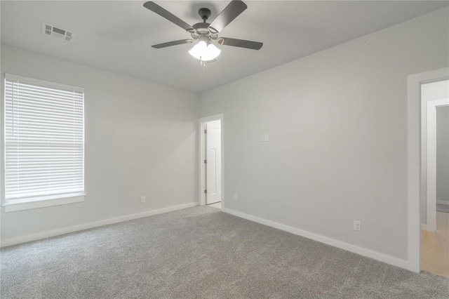 empty room featuring light colored carpet, visible vents, ceiling fan, and baseboards