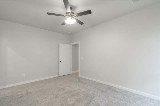 spare room with light colored carpet, baseboards, and a ceiling fan