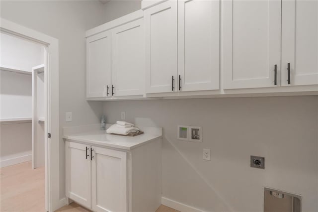 laundry room with washer hookup, hookup for an electric dryer, light wood-style flooring, baseboards, and cabinet space