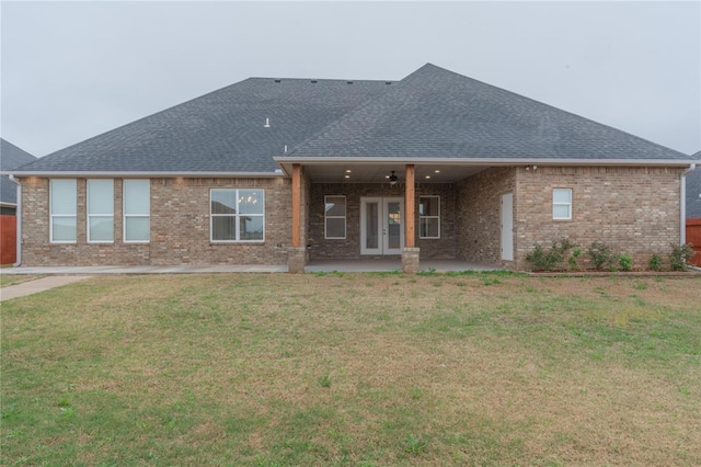 back of property with a ceiling fan, roof with shingles, french doors, a yard, and a patio area