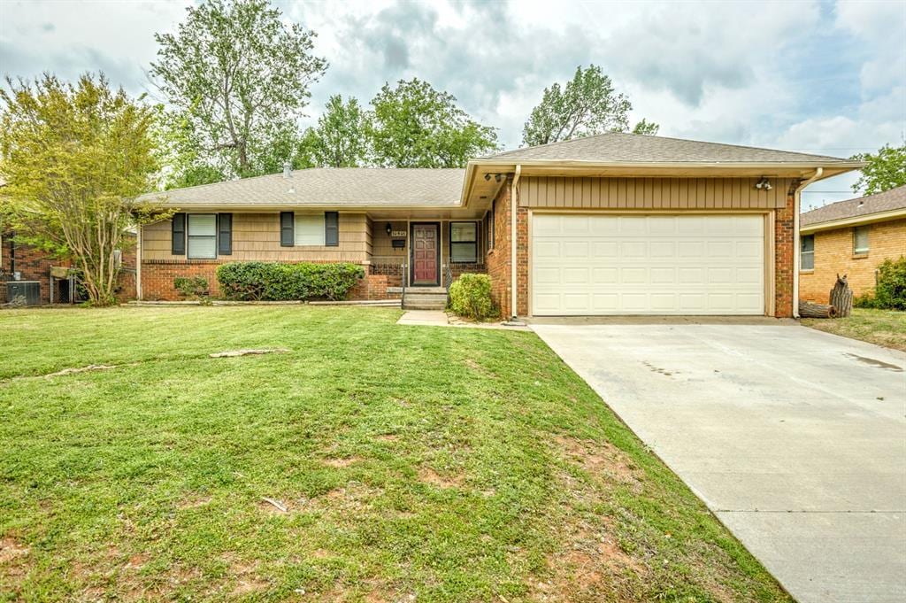 ranch-style home featuring a garage, driveway, a front lawn, and brick siding