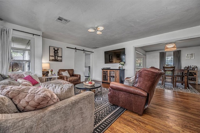 2837 Cambridge Ct, Oklahoma City, OK 73116 - living area featuring visible vents, a barn door, wood finished floors, and a textured ceiling