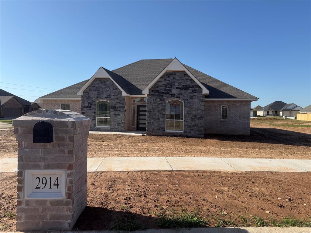 french country style house with brick siding and roof with shingles