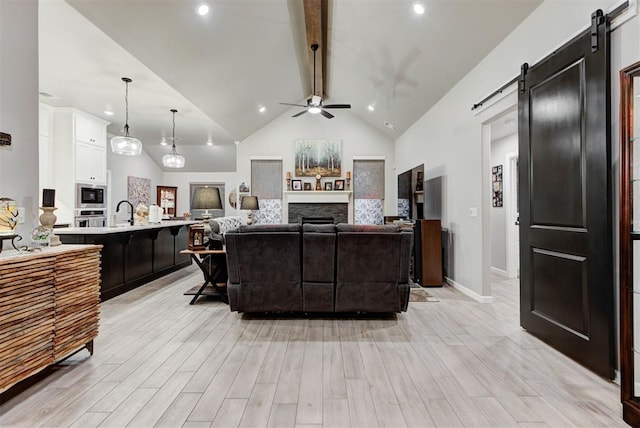 5513 Carmel Creek Dr, Mustang, OK 73064 - living area featuring a barn door, a ceiling fan, beam ceiling, light wood-style flooring, and high vaulted ceiling