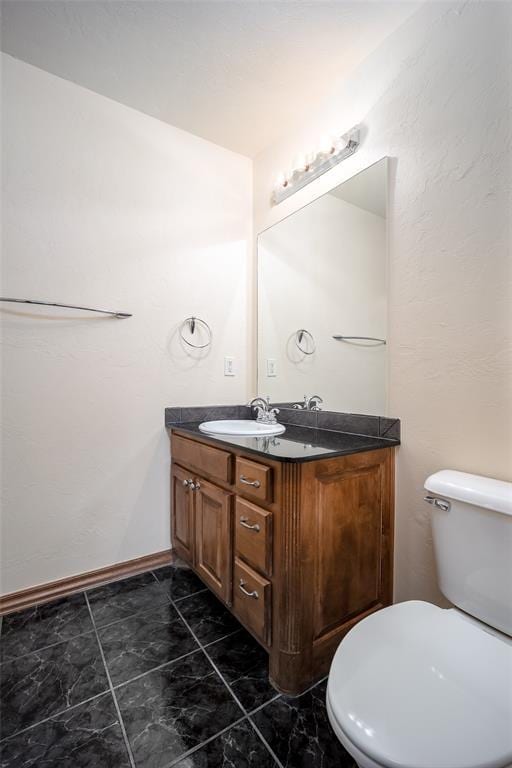 bathroom featuring toilet, vanity, and baseboards