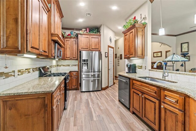 11609 SW 14th St, Yukon, OK 73099 - kitchen with appliances with stainless steel finishes, a sink, backsplash, brown cabinets, and light stone counters