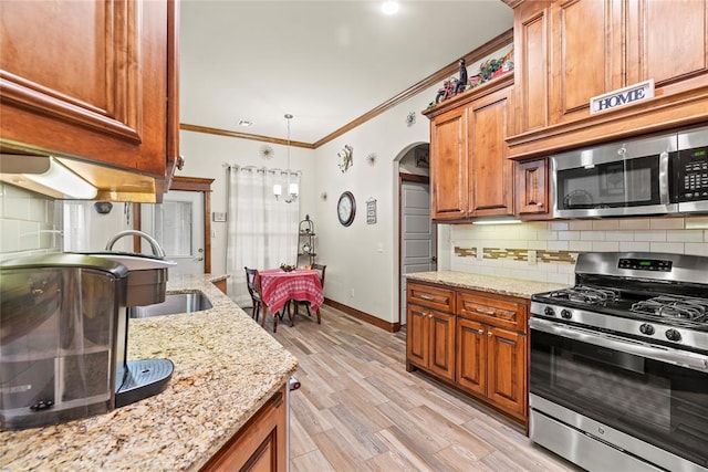 11609 SW 14th St, Yukon, OK 73099 - kitchen with stainless steel appliances, arched walkways, crown molding, brown cabinets, and decorative backsplash