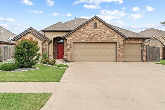 11609 SW 14th St, Yukon, OK 73099 - french country inspired facade with a garage, driveway, brick siding, and a shingled roof
