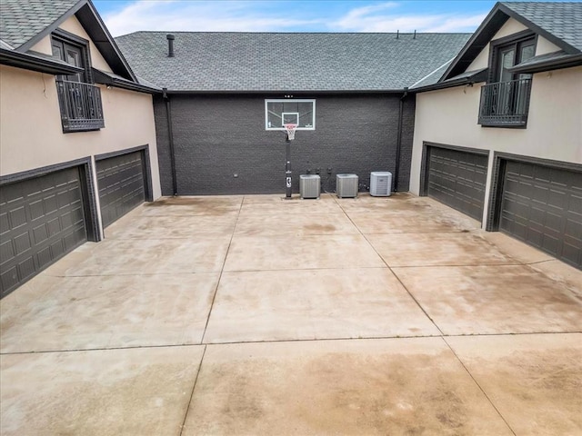 view of home's exterior featuring concrete driveway, roof with shingles, and a balcony