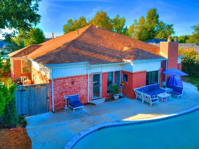 1821 Coventry Ln, Nichols Hills, OK 73120 - back of house featuring brick siding, roof with shingles, an outdoor living space, a chimney, and a patio