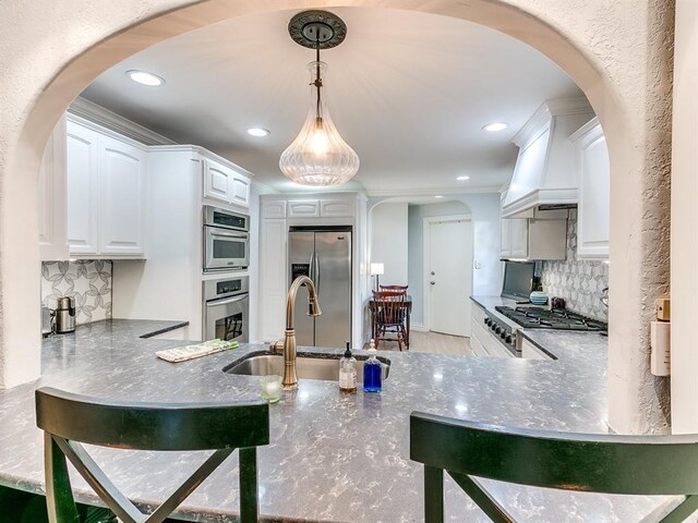 1821 Coventry Ln, Nichols Hills, OK 73120 - kitchen featuring stainless steel appliances, arched walkways, premium range hood, decorative backsplash, and recessed lighting