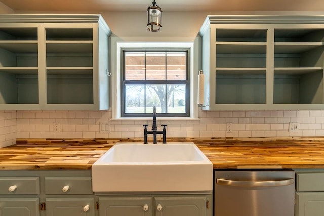 kitchen featuring tasteful backsplash, wood counters, open shelves, stainless steel dishwasher, and a sink