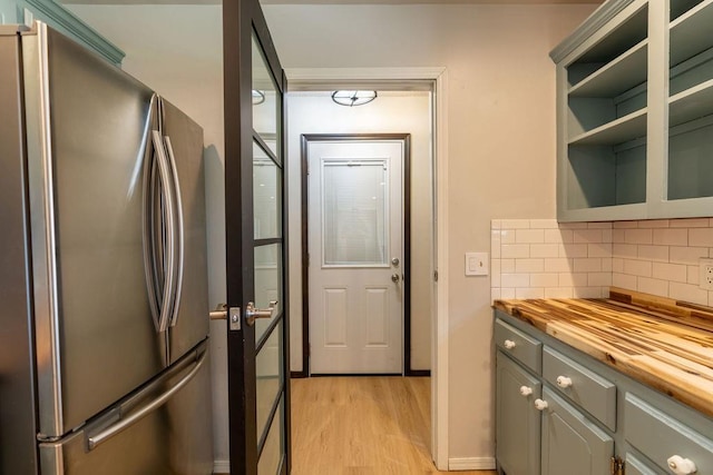 kitchen featuring freestanding refrigerator, butcher block counters, gray cabinetry, light wood-style floors, and decorative backsplash