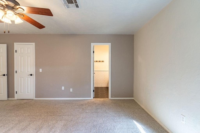 unfurnished room with ceiling fan, a textured ceiling, visible vents, carpet floors, and baseboards