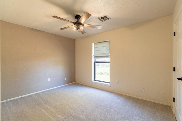 unfurnished room with visible vents, ceiling fan, light colored carpet, and baseboards