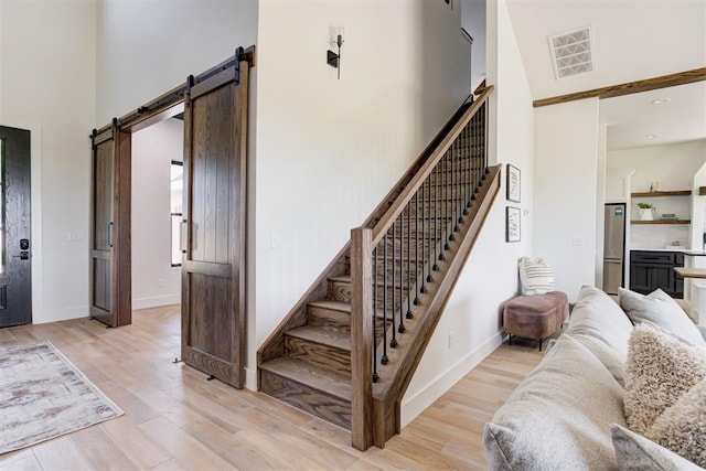 2223 Wintercreek Blvd, Blanchard, OK 73010 - stairs with a barn door, a high ceiling, and wood finished floors