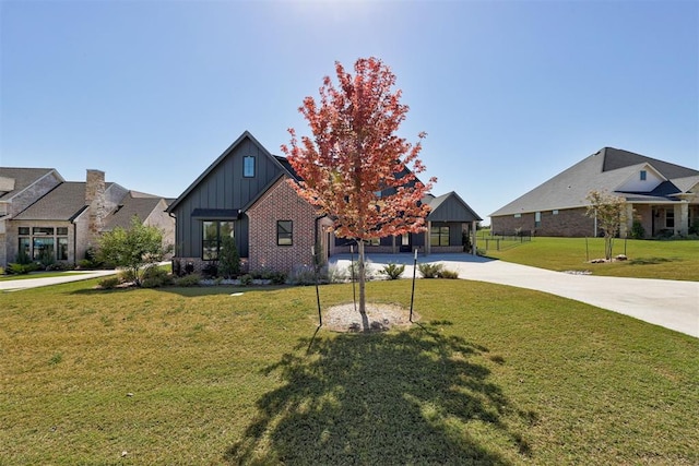 2223 Wintercreek Blvd, Blanchard, OK 73010 - view of front of property with board and batten siding, a front yard, concrete driveway, and brick siding
