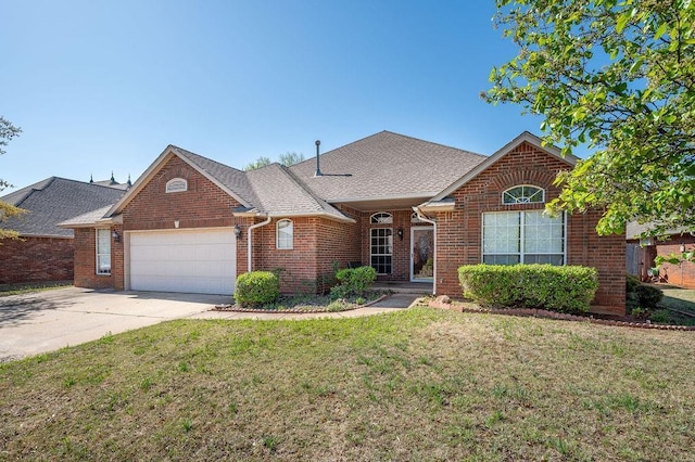 view of front of home featuring a front yard, a shingled roof, a garage, brick siding, and driveway