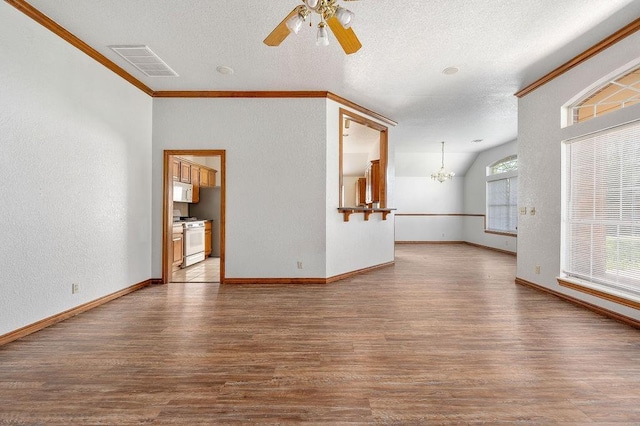 spare room with ceiling fan with notable chandelier, ornamental molding, visible vents, wood finished floors, and a textured wall