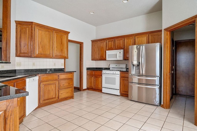 kitchen with white appliances, brown cabinets, and dark countertops