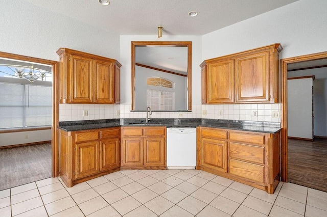 kitchen with brown cabinetry, a sink, and white dishwasher