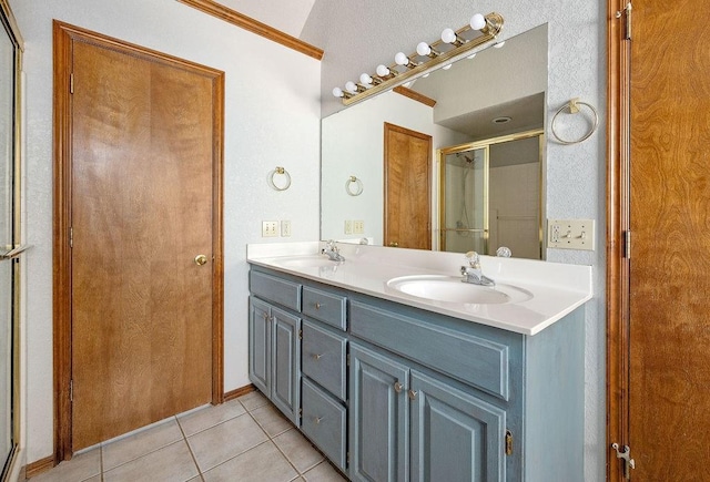 full bathroom with double vanity, ornamental molding, tile patterned floors, a shower stall, and a sink
