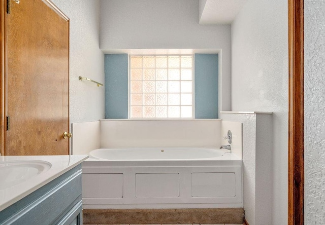 bathroom featuring a bath, vanity, and a textured wall