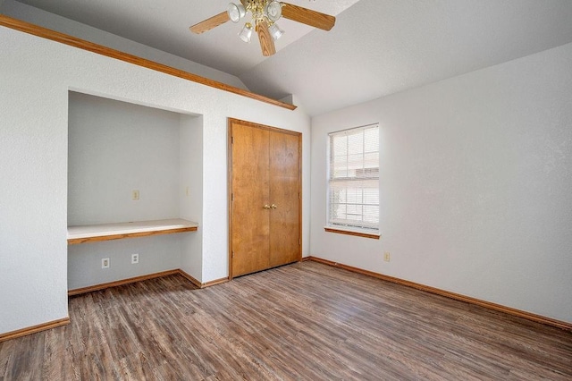unfurnished bedroom with baseboards, a closet, vaulted ceiling, and wood finished floors