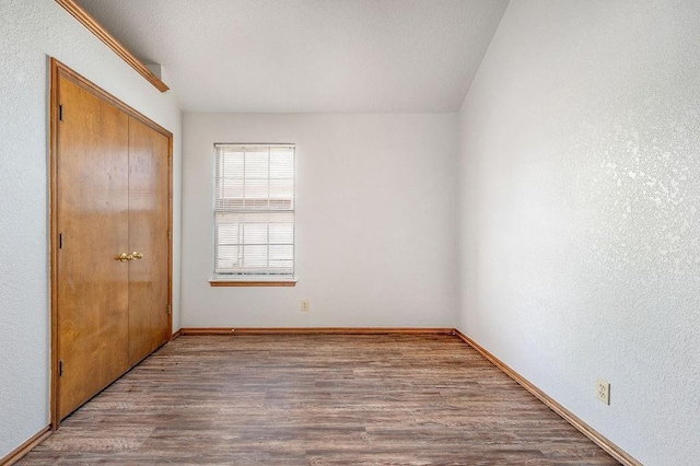 unfurnished bedroom featuring a closet, baseboards, and wood finished floors
