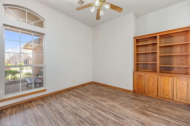 spare room with wood finished floors, baseboards, a ceiling fan, and visible vents