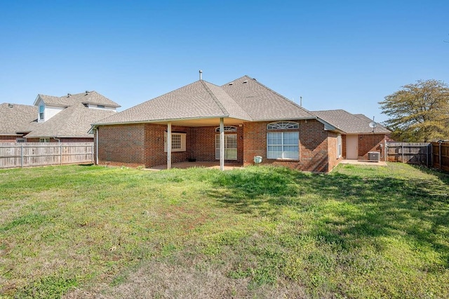 rear view of property featuring a yard, a fenced backyard, central AC, and brick siding