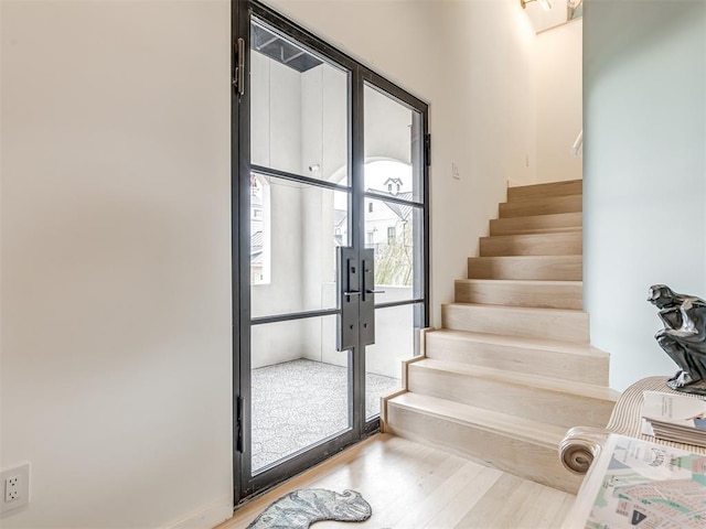 staircase featuring wood finished floors and french doors