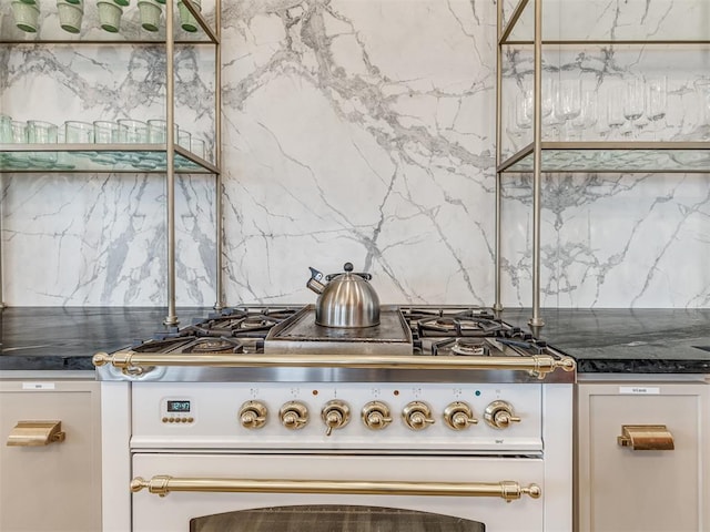 kitchen with gas range oven, dark countertops, and tasteful backsplash