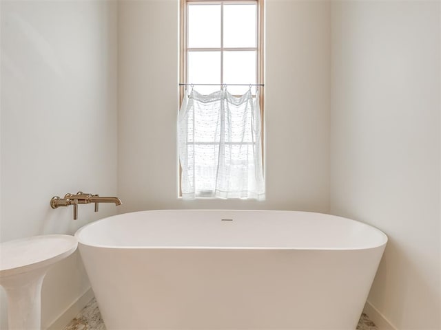 full bathroom featuring a soaking tub and baseboards