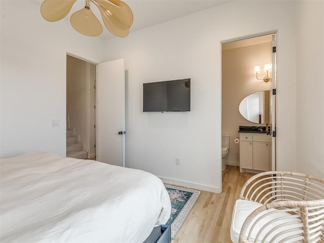 bedroom with connected bathroom and light wood-style floors
