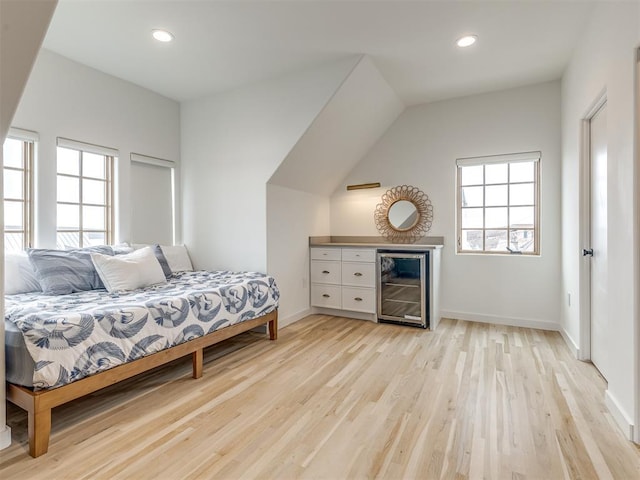 bedroom featuring light wood-type flooring, baseboards, recessed lighting, a bar, and beverage cooler