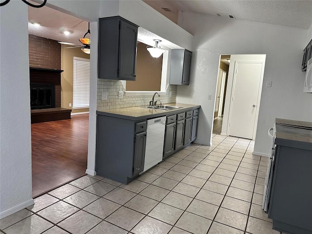 kitchen with light tile patterned flooring, vaulted ceiling, a sink, dishwasher, and ceiling fan