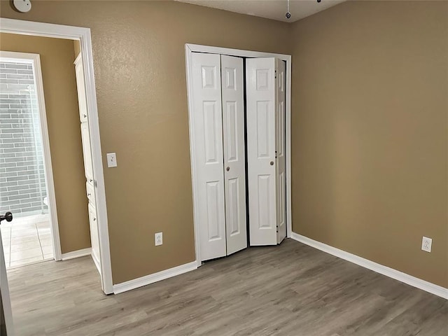 unfurnished bedroom with a closet, baseboards, and light wood-style floors