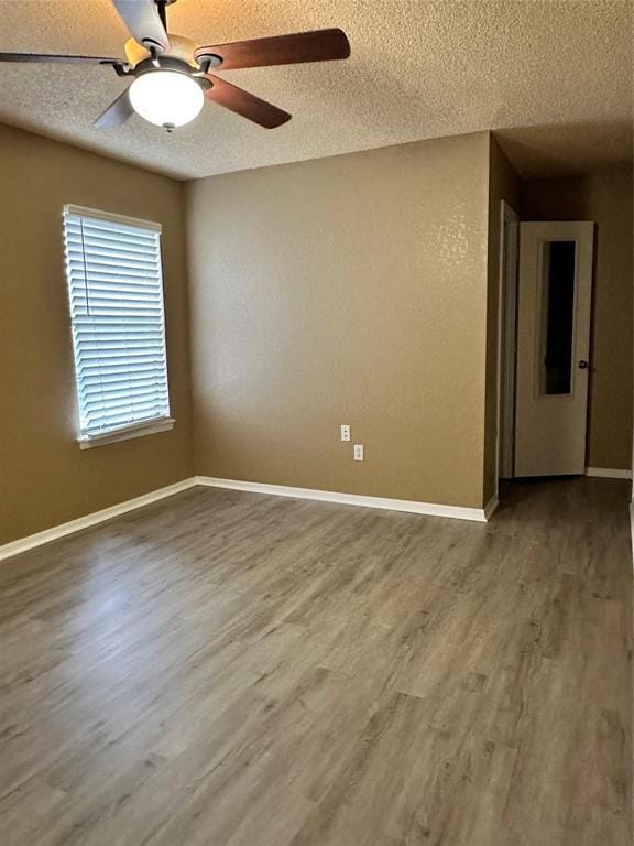 unfurnished room featuring a textured ceiling, baseboards, and wood finished floors