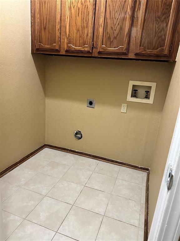 laundry area with washer hookup, baseboards, electric dryer hookup, cabinet space, and light tile patterned floors