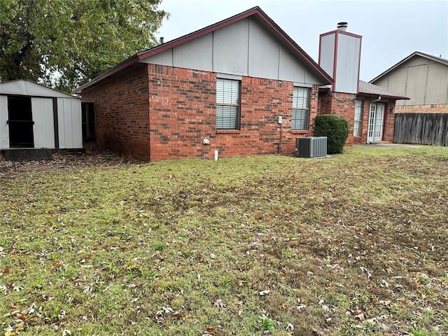 rear view of house with an outbuilding, central AC unit, brick siding, and a shed