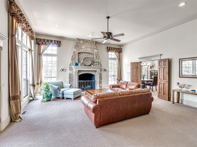 carpeted living room with ornamental molding, visible vents, a ceiling fan, and a stone fireplace