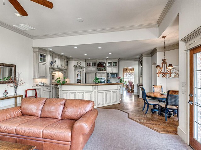 living area featuring a wealth of natural light, visible vents, crown molding, and wood finished floors