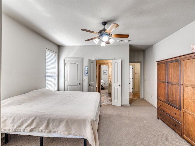 bedroom with a ceiling fan, light carpet, and a textured ceiling