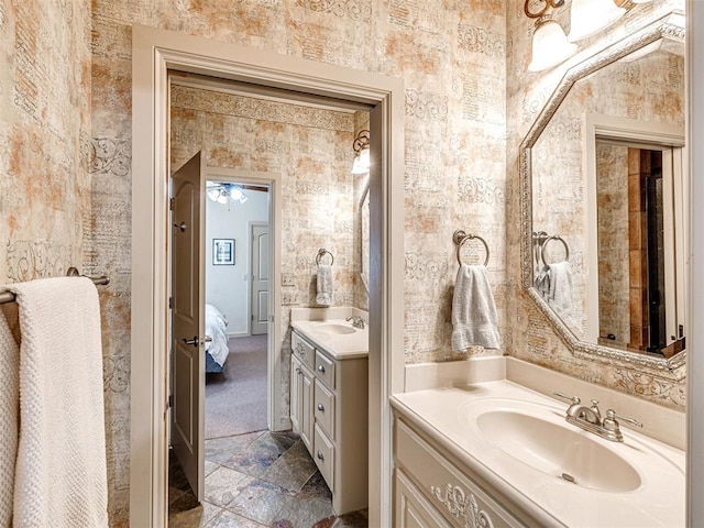 full bathroom with ensuite bath, stone finish flooring, a sink, and two vanities