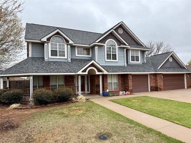 view of front facade featuring driveway, a front yard, roof with shingles, an attached garage, and brick siding