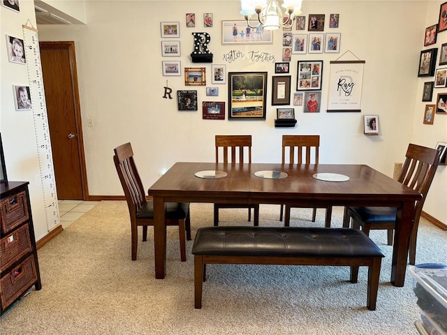 dining space featuring light carpet, baseboards, a notable chandelier, and light tile patterned floors