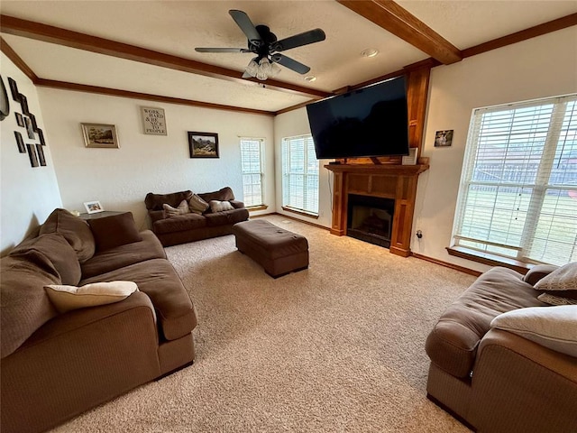 carpeted living room with a fireplace, ceiling fan, baseboards, and beam ceiling
